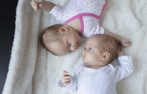 PHoto of two babies. One wearing pink, one wearing blue