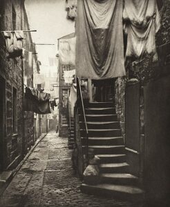 Black and white photo of narrow, dark, residential street