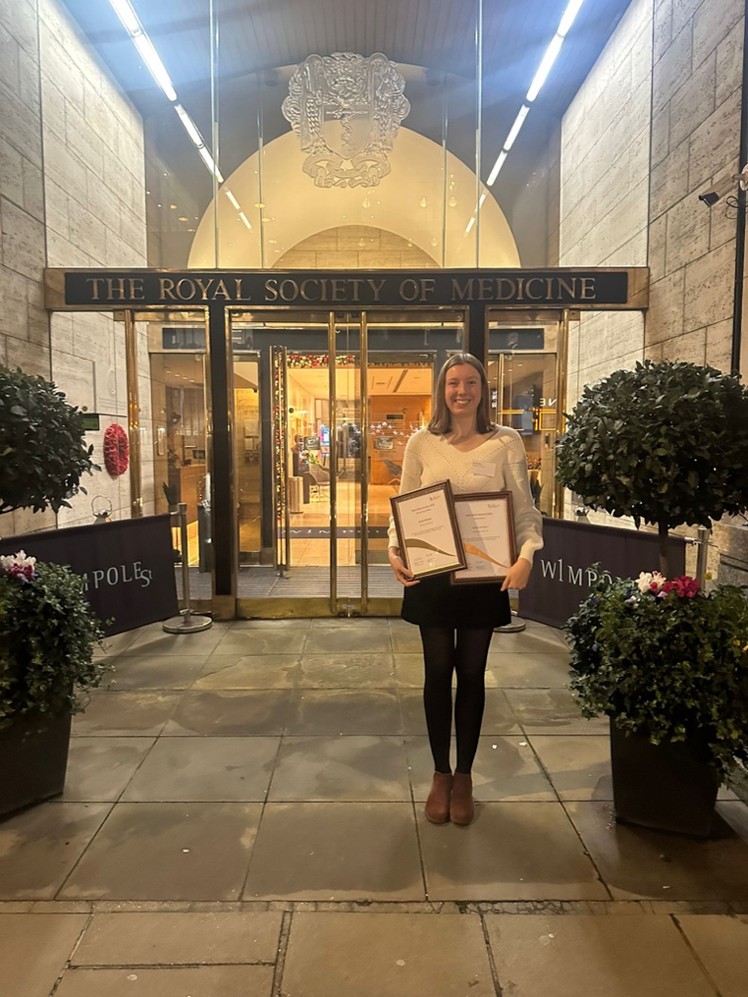 Grace holding her Rob Clarke Presentation award outside the Royal Society of Medicine.